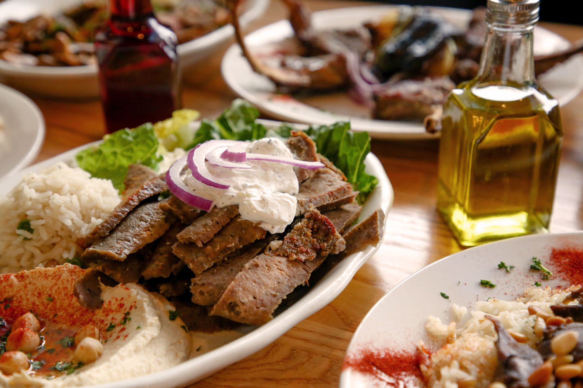 Mediterranean meal spread with grilled meat, rice, hummus, and olive oil